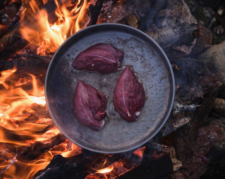 Venison fillets in a pan over the campfire