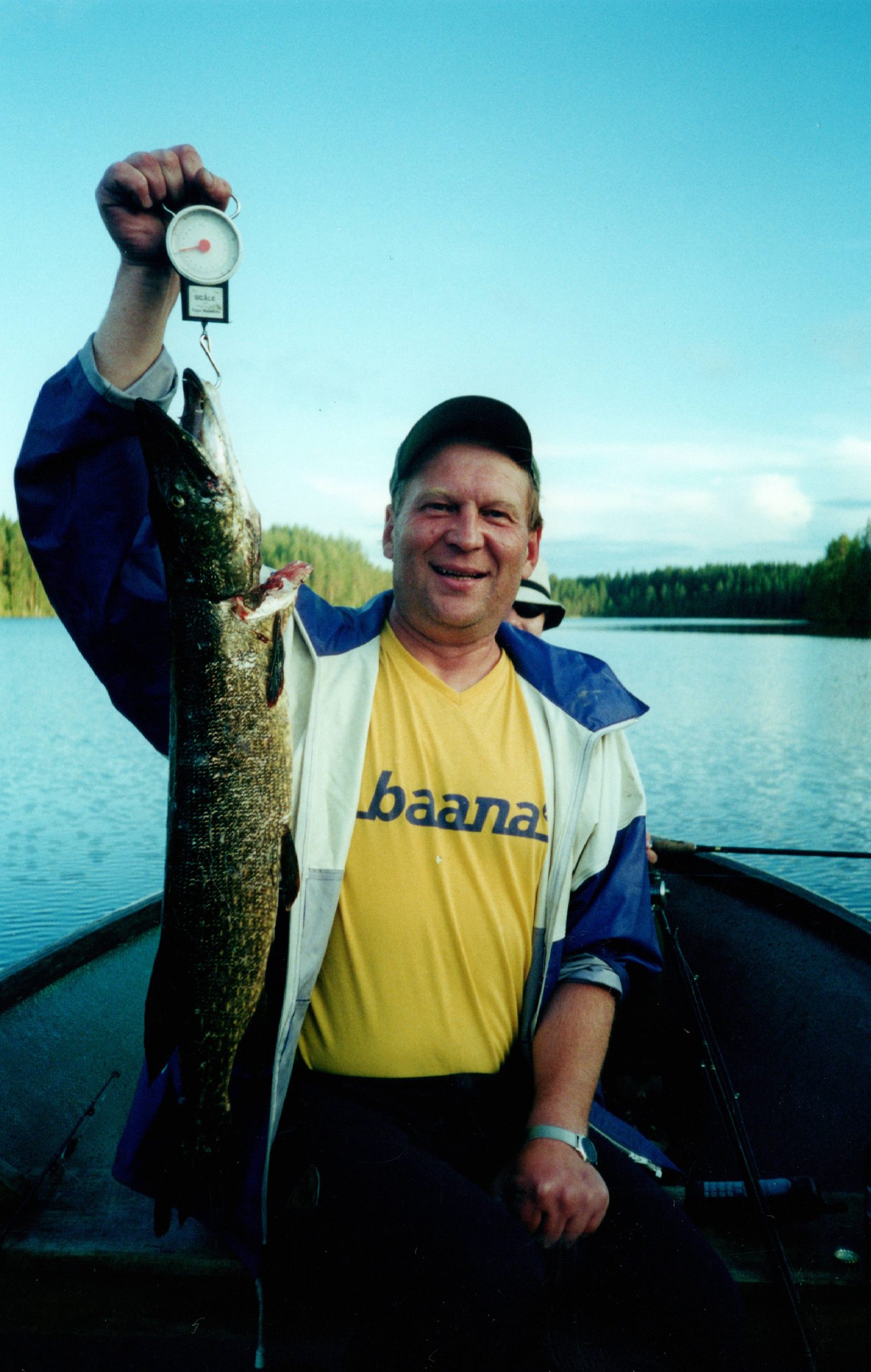 Angler weighing a pike in the boat on a calm lake