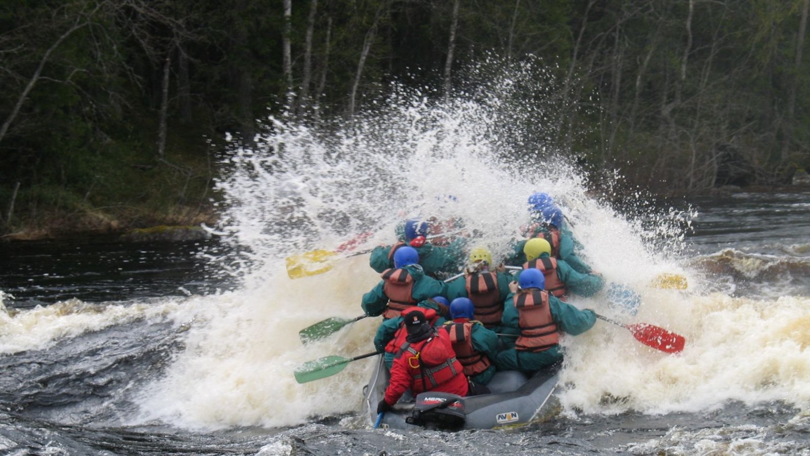 Raft crew hitting a wave on the Ruunaa rapids, spray flying